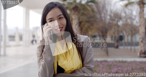 Image of Young woman standing talking on her mobile phone