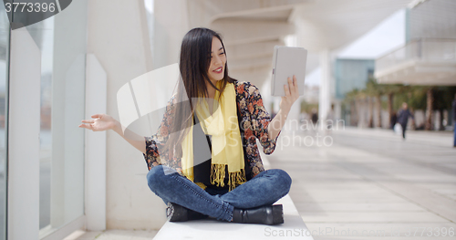 Image of Smiling woman waving at her tablet computer