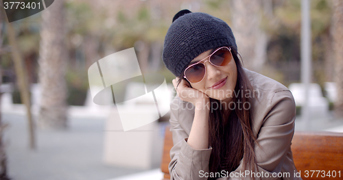 Image of Happy relaxed trendy woman sitting daydreaming