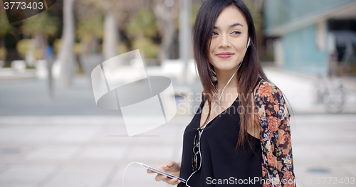 Image of Young woman walking listening to music