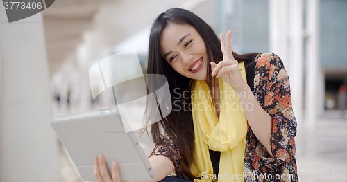 Image of Cheerful female gesturing for tablet camera