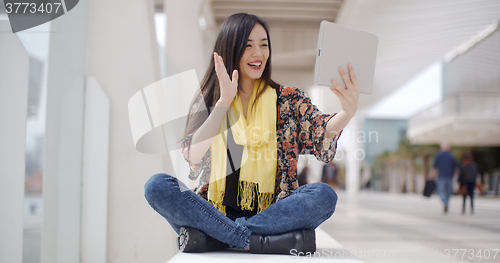 Image of Smiling woman waving at her tablet computer