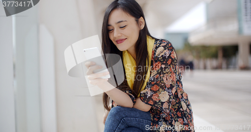 Image of Chic young woman reading a mobile message