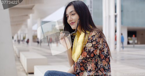 Image of Thoughtful young woman sitting on a promenade