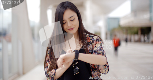 Image of Young woman looking at the time with a smile