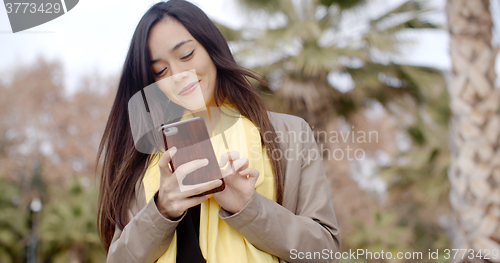 Image of Happy young woman sending a text message
