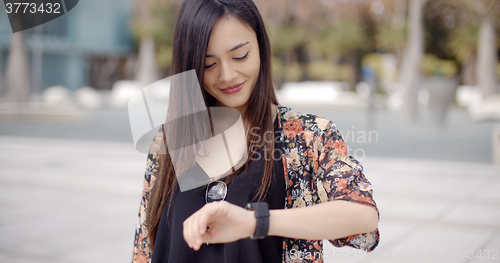 Image of Young woman looking at the time with a smile