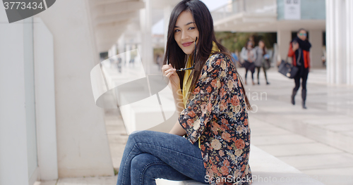 Image of Thoughtful young woman sitting on a promenade