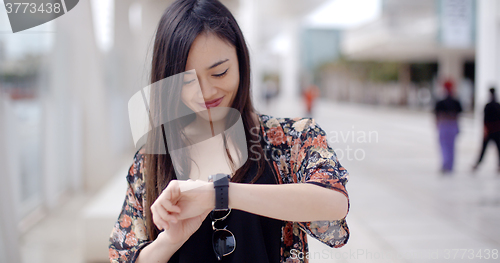 Image of Young woman looking at the time with a smile