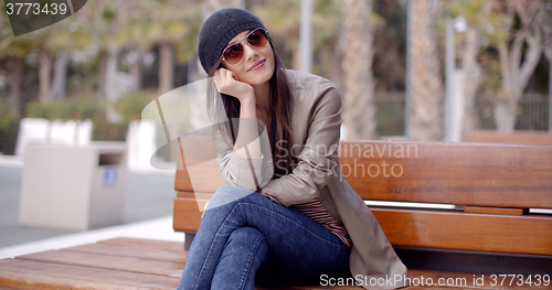 Image of Happy relaxed trendy woman sitting daydreaming