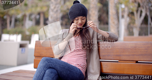 Image of Trendy young woman relaxing on a park bench