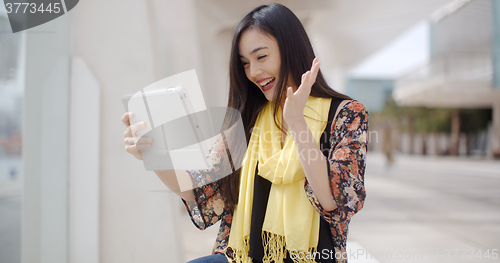 Image of Excited woman waving at her tablet computer