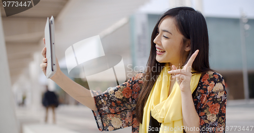 Image of Cheerful female gesturing for tablet camera