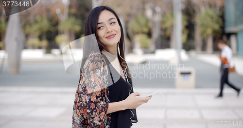 Image of Young woman walking listening to music