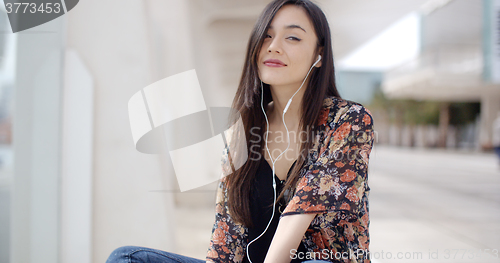 Image of Trendy young woman listening to music in town