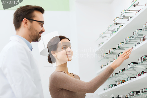 Image of woman showing glasses to optician at optics store