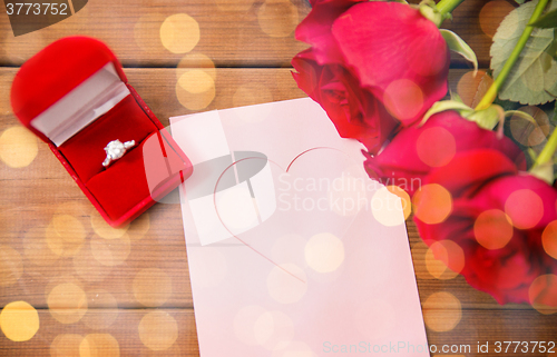 Image of close up of diamond ring, roses and greeting card