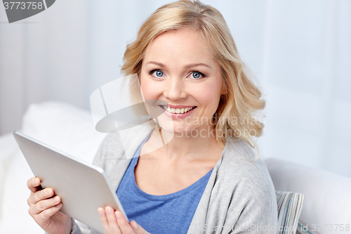 Image of happy middle aged woman with tablet pc at home