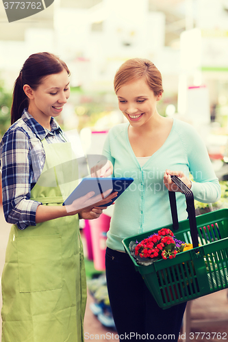 Image of happy women with tablet pc in greenhouse