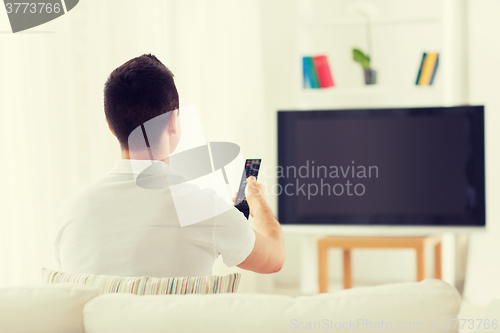 Image of man watching tv and changing channels at home