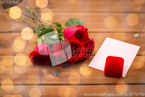 Image of close up of gift box, red roses and greeting card