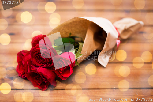 Image of close up of red roses bunch wrapped into paper