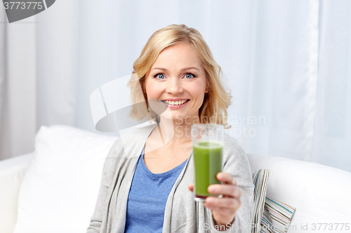 Image of happy woman drinking green juice or shake at home