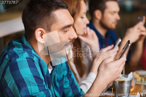 Image of friends with smartphones dining at restaurant