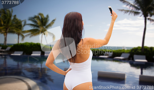 Image of young woman taking selfie with smartphone on beach