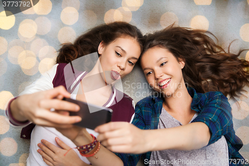 Image of happy teenage girls on floor and taking selfie