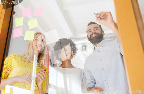 Image of happy creative team writing on stickers at office