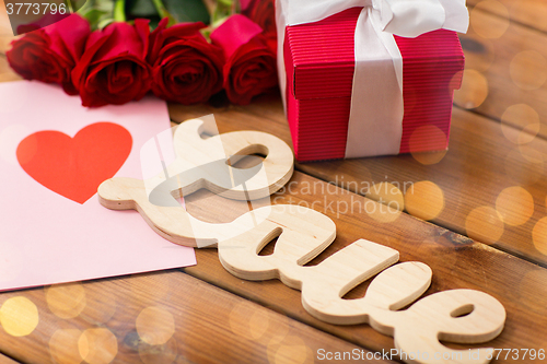 Image of close up of gift box, red roses and greeting card