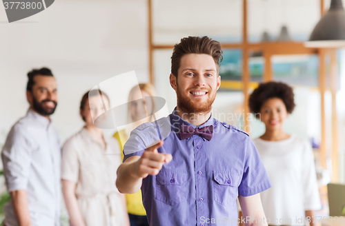 Image of happy man pointing finger at you over office team
