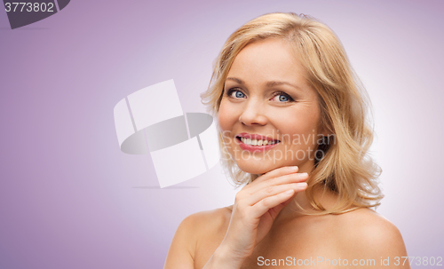Image of smiling woman with bare shoulders touching face