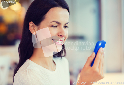 Image of close up of smiling woman with smartphone at cafe