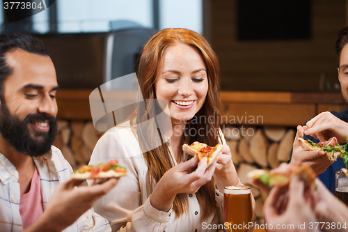 Image of friends eating pizza with beer at restaurant