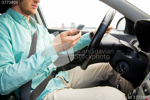 Image of close up of man with smartphone driving car