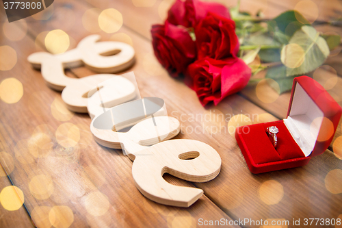 Image of close up of diamond ring, red roses and word love