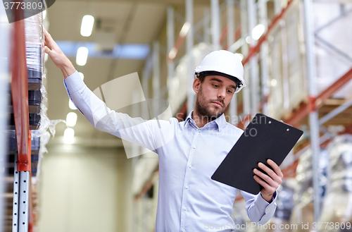 Image of happy businessman with clipboard at warehouse