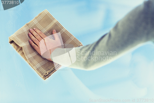 Image of close up of woman hand cleaning window with cloth