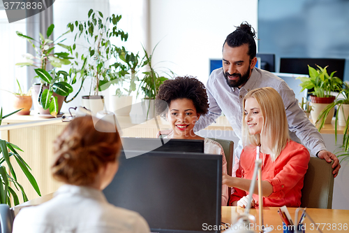 Image of happy creative team with computer in office