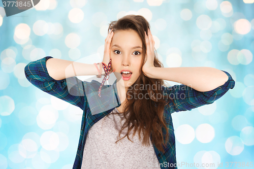 Image of happy pretty teenage girl holding to head