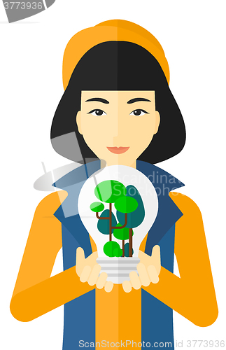 Image of Woman with lightbulb and trees inside.