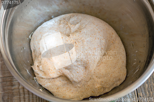 Image of Homemade bread dough in a metal bowl.