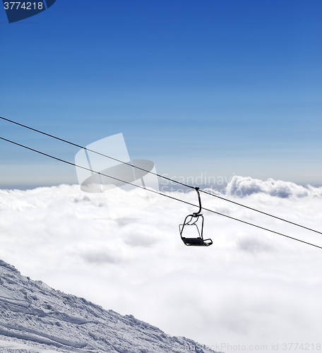 Image of Ski slope, chair-lift and mountains under clouds