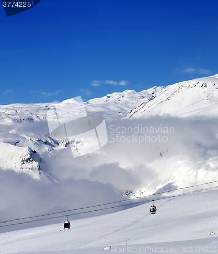 Image of Off-piste snowy slope and cable car at sun day