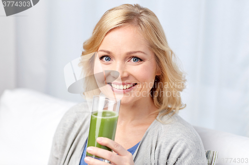 Image of happy woman drinking green juice or shake at home