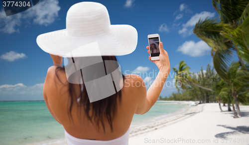 Image of woman taking selfie with smartphone on beach