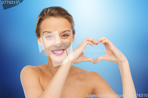 Image of smiling young woman showing heart shape hand sign