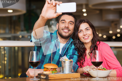 Image of couple taking selfie by smartphone at restaurant